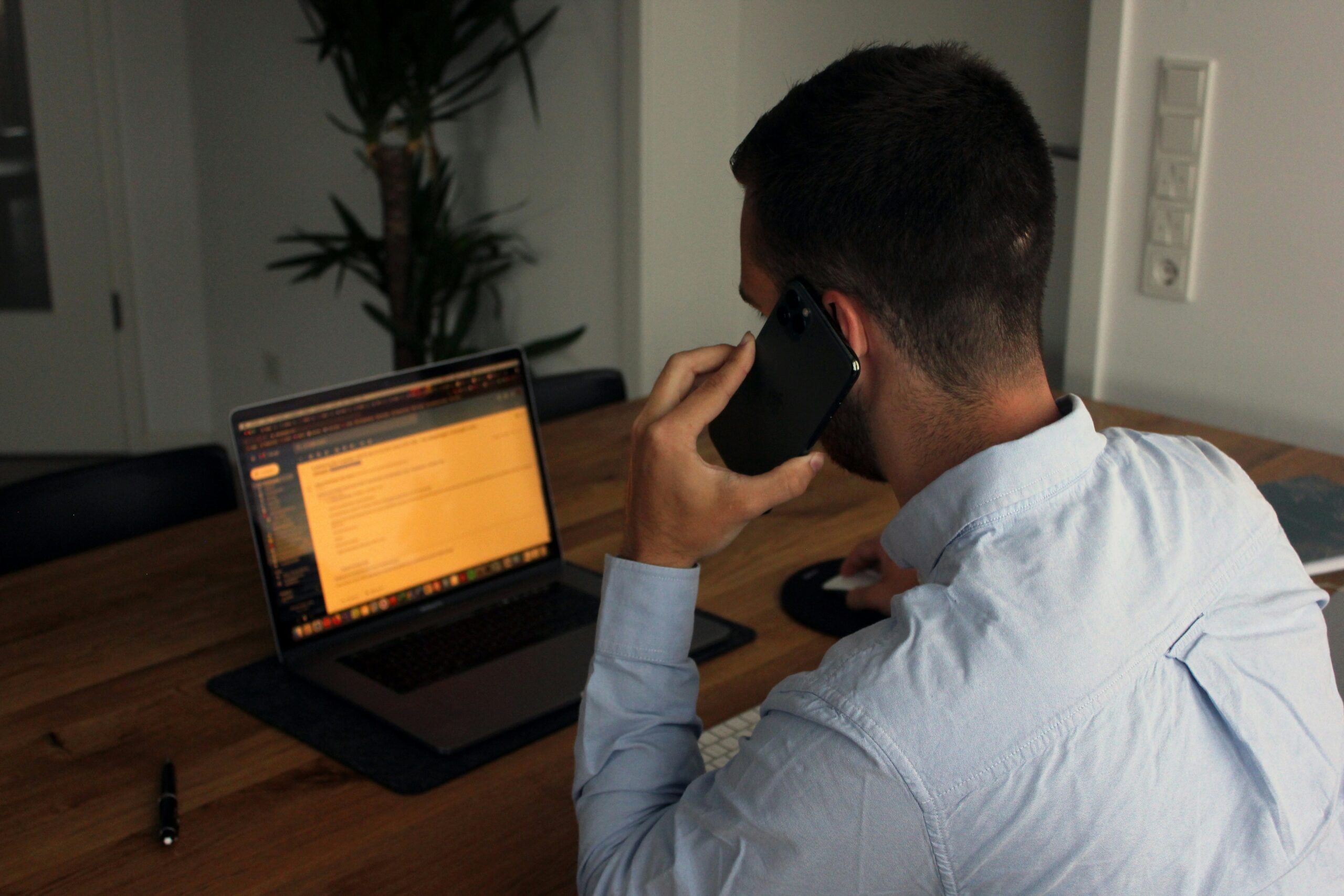 Person on a phone call, in front of a laptop. Photo by David Hahn on Unsplash